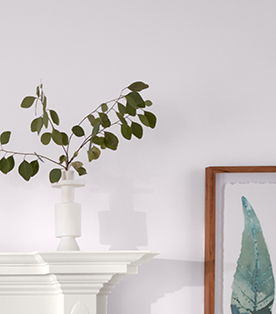 Corner of fireplace mantle with leaves in a vase against a Gentle Violet wall.