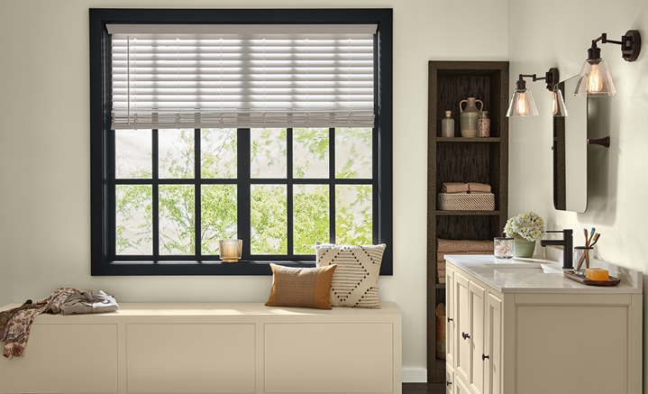 Bright, neutral bathroom with window seat, dark, wood-paned windows and built-in, vertical linen shelf.