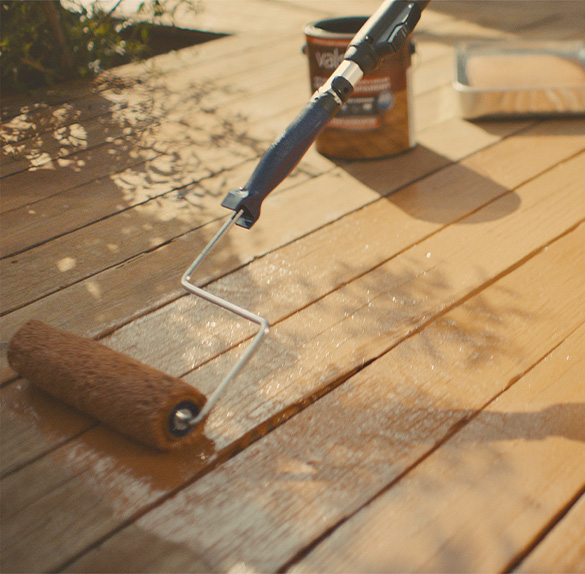 Roller painting with lighter neutral over a darker neutral and textured wall.