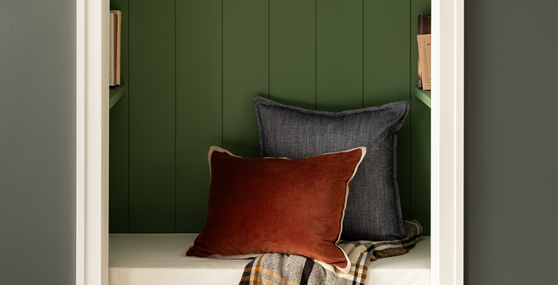 Close-up of book nook in Earthy Greens with Northern Glen paneling, bench with pillows and Warm Eucalyptus exterior wall. 