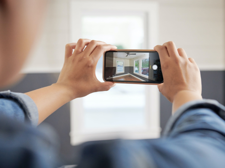 Hands holding camera in front of a scene. In viewfinder you can see how the Lowe’s Color Visualizer works.